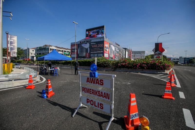 Police personnel man a roadblock restricting access to Pasar Borong Kuala Lumpur and Kampung Selayang on April 21, 2020. — Picture by Hari Anggara