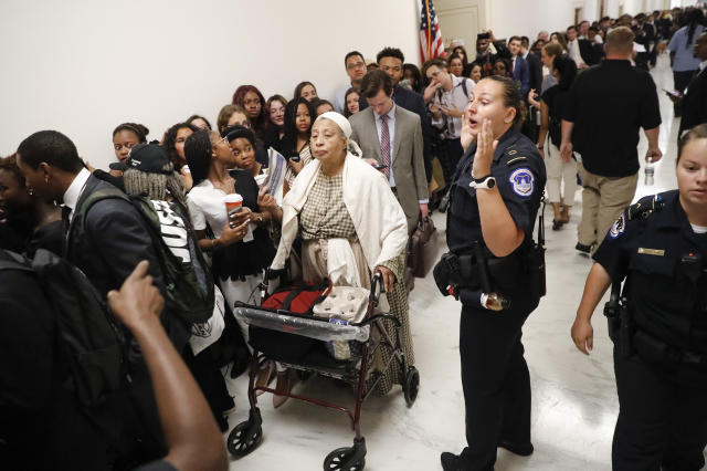 Capitol Police officer speaks to the crowd in the hallway waiting to get into hearing about reparation for the descendants of slaves at the House Judiciary Subcommittee on the Constitution, Civil Rights and Civil Liberties, at the Capitol in Washington, Wednesday, June 19, 2019. (AP Photo/Pablo Martinez Monsivais)