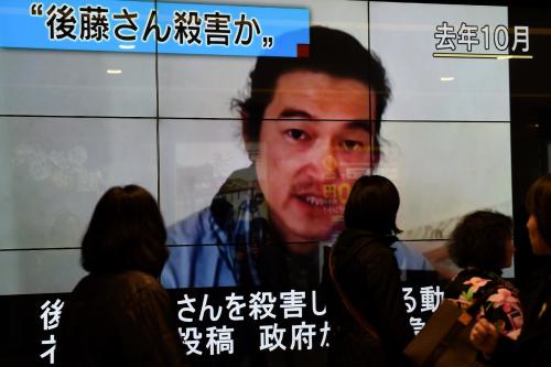 Tokyo residents walk past a big screen reporting that Islamic State militants had killed Kenji Goto, whose poignant tweet on the virtue of being calm is spreading on social media