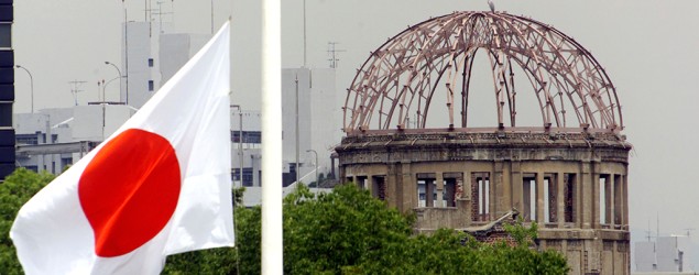 The Japanese national flag flutters at half-mast in the foreground of the atomic bomb dome at the Hiroshima Peace Memorial Park, in western Japan August 6, 1998. REUTERS/Kimimasa Mayama/File Photo