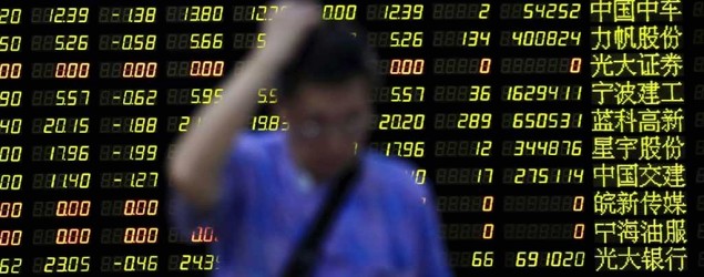 An investor stands in front of an electronic board showing stock information at a brokerage house in Shanghai, China. (Aly Song/Reuters)