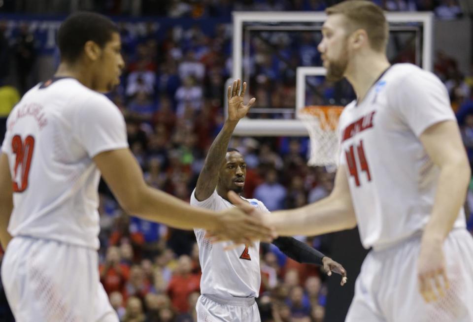 Louisville's Russ Smith (2) celebrates with teammates Wayne Blackshear (20) and Stephan Van Treese (44) during a time out in the first half of an NCAA Midwest Regional semifinal college basketball tournament game against the Kentucky Friday, March 28, 2014, in Indianapolis. (AP Photo/Michael Conroy)
