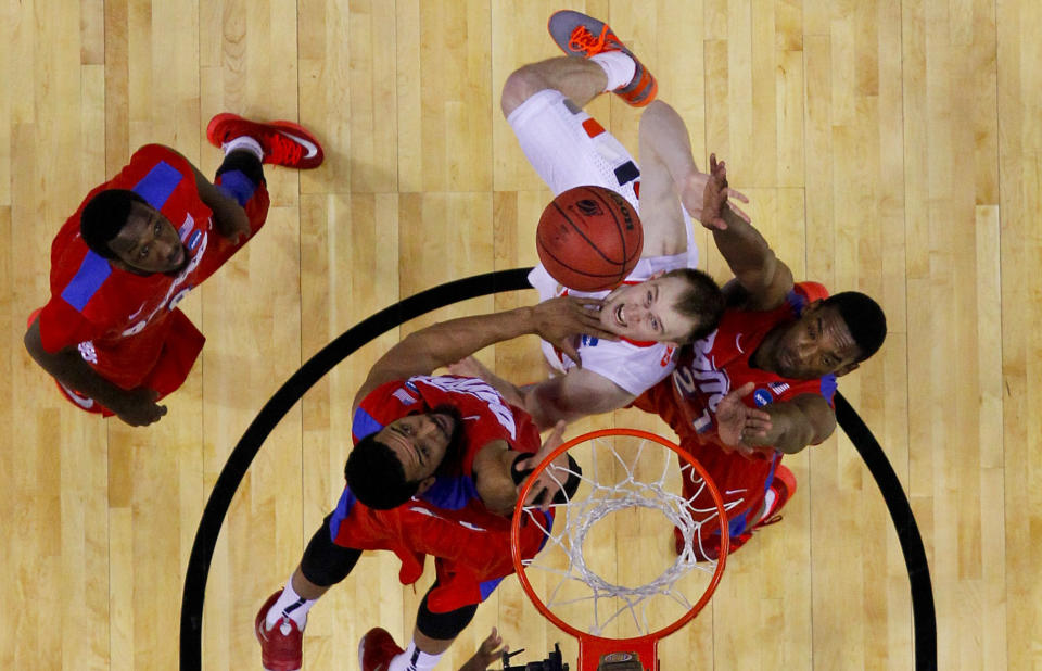 Syracuse's Trevor Cooney (10) shoots between Dayton's Devon Scott, second from left, and Dyshawn Pierre, right, as Khari Price, left, watches during the first half of a third-round game in the NCAA men's college basketball tournament in Buffalo, N.Y., Saturday, March 22, 2014. (AP Photo/Bill Wippert)