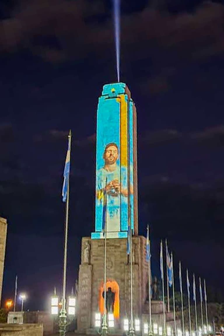 El Monumento a la Bandera con los colores patrios y la figura de Leo Messi