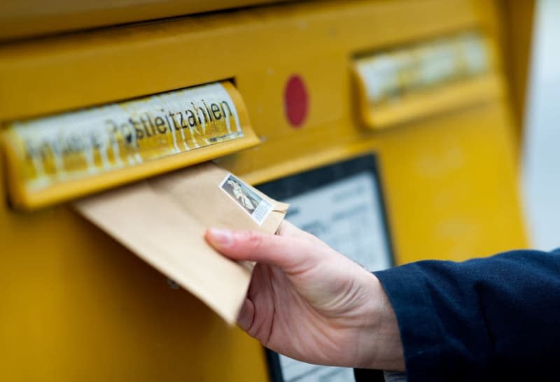 A person drops a letter into a letterbox. Tens of thousands of people in Germany complained about delayed or lost letters and parcels last year, the Federal Network Agency reported on Wednesday. Monika Skolimowska/dpa