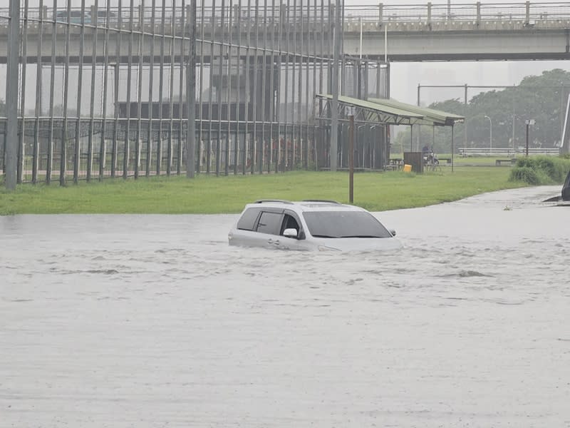 新北市20日下午下起大雷雨，造成部分地區道路積淹水，江子翠水門堤外道路還有車子受困，幾乎滅頂，所幸經確認，車內無人。（中央社）