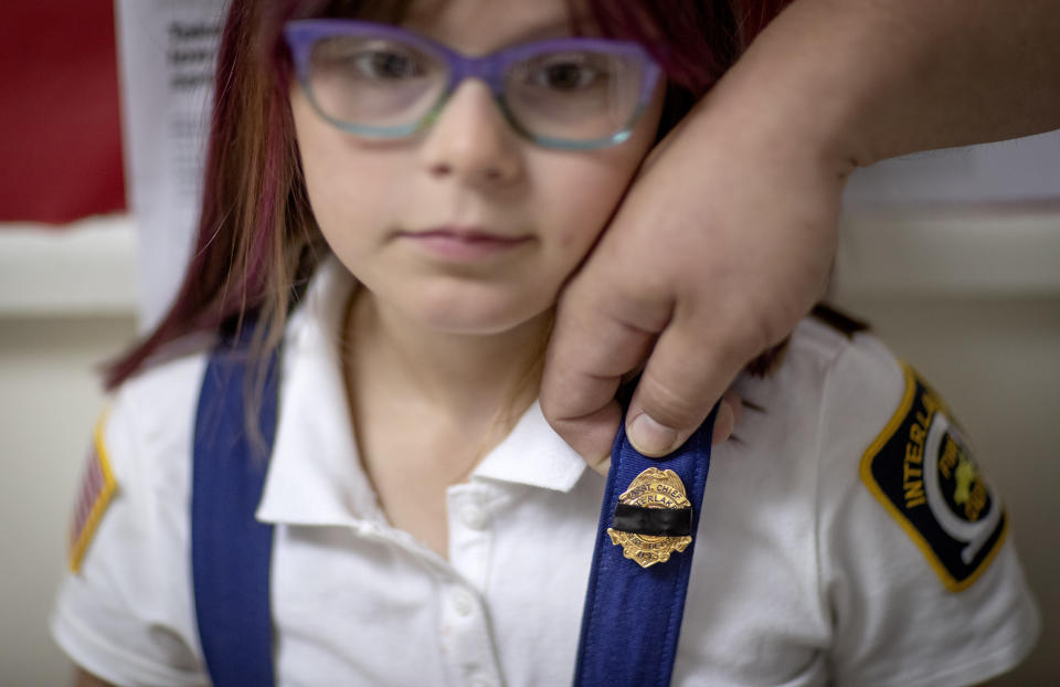 Dani Nelson, 7, wears a junior fire badge covered in black tape, a gesture of mourning, by her father, Chris Nelson, a member of the Enfield Volunteer Fire Company where Sgt. James Johnston once served, before a memorial procession for him in Enfield, N.Y., Saturday, Aug. 31, 2019. Johnston, an explosive ordnance disposal specialist, had been killed along with a Green Beret on June 25 in Uruzgan Province in south-central Afghanistan. (AP Photo/David Goldman)