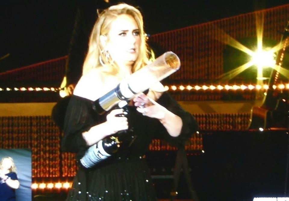 Adele looking serious while holding a T-shirt gun