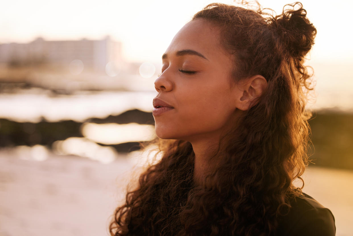 Woman standing by water and breathing deeply