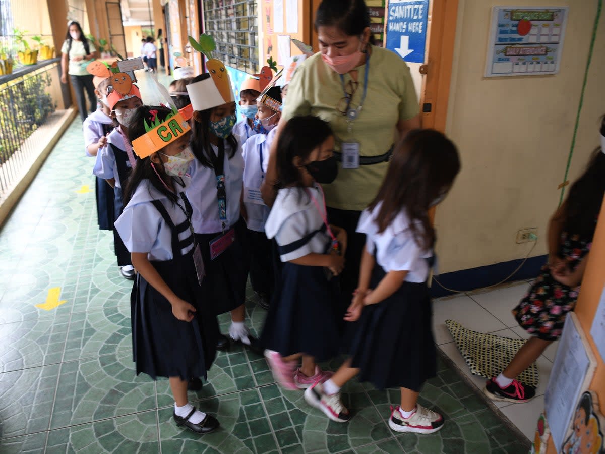 A teacher watches her students walk inside a classroom after a short break at the start of classes at a school in Quezon City, suburban Manila on 22 August 2022  (AFP via Getty Images)