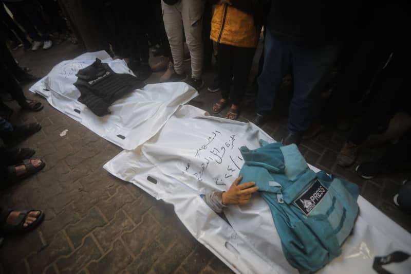 Press vests are placed over the bodies of Palestinian journalists Hamza Dahdouh and Mustafa Thuraya, who were killed in an Israeli air strike on Rafah. Hamza is the son of Al-Jazeera bureau chief in Gaza, Wael Dahdouh, who has previously lost his wife, two other children and a grandson and was injured himself during the war. Mohammed Talatene/dpa