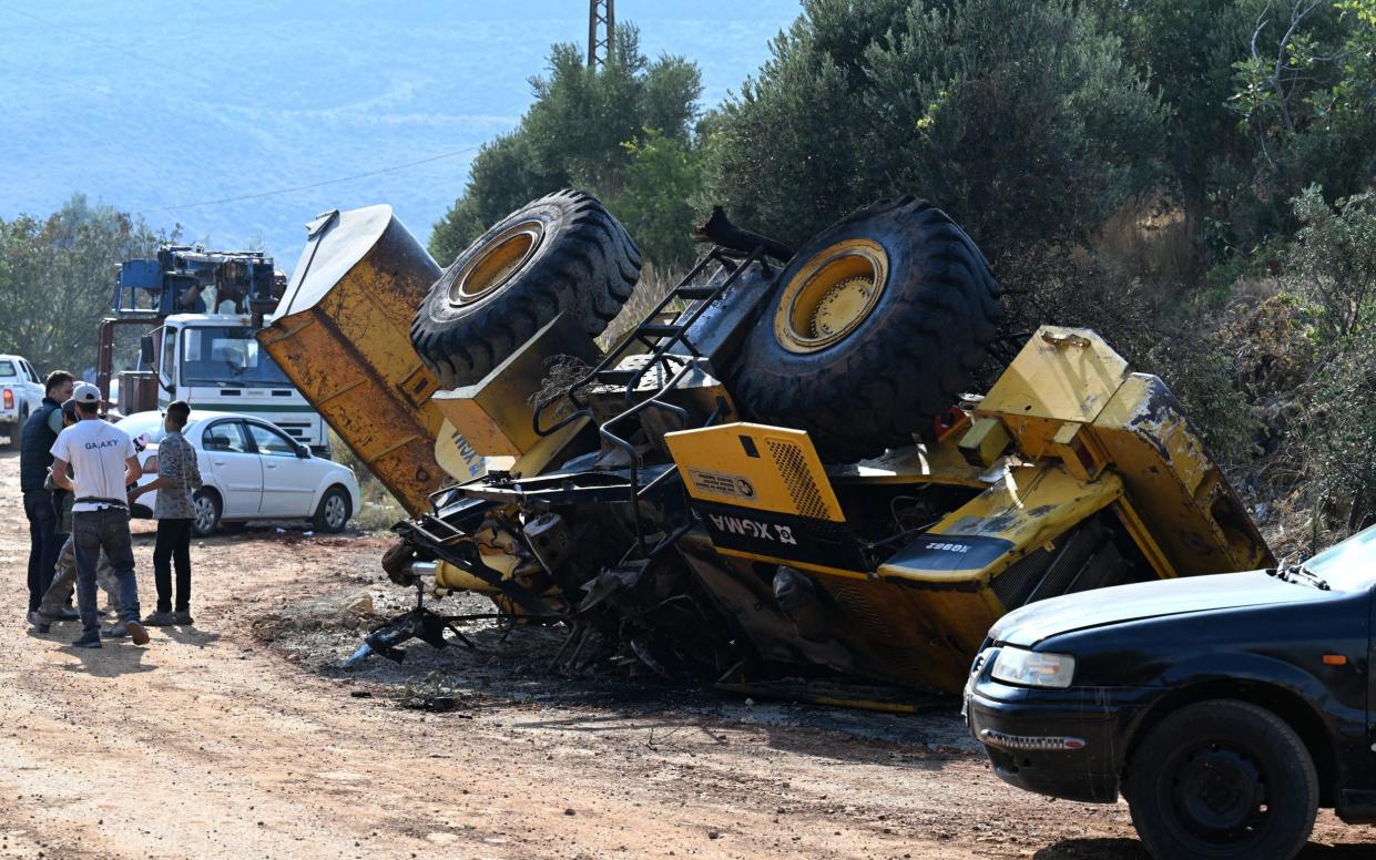 An overturned bulldozer, which has been partially burned