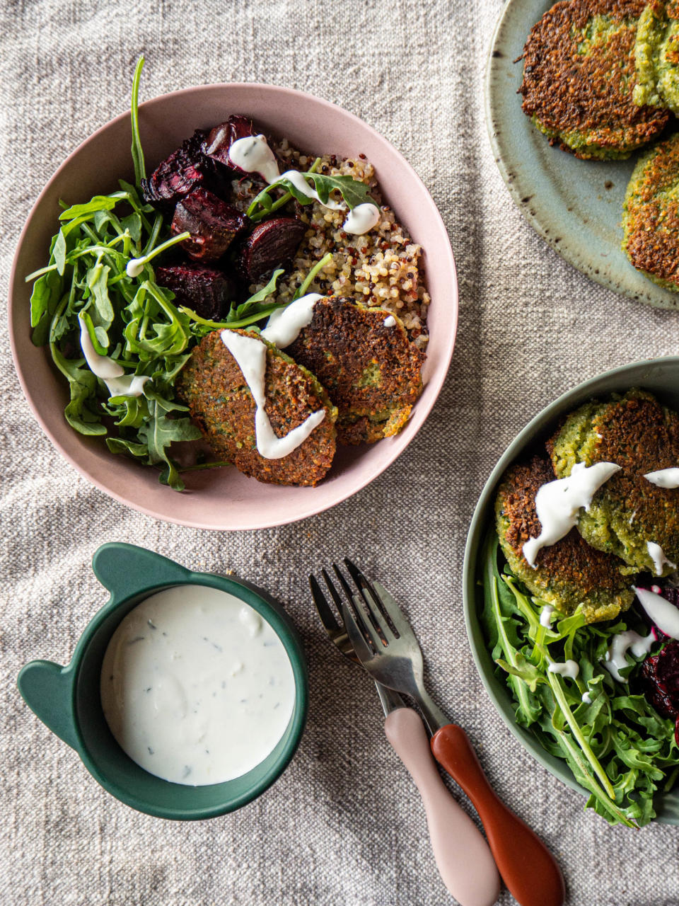 A meal with falafel, quinoa, beets, salad, and a bowl of sauce