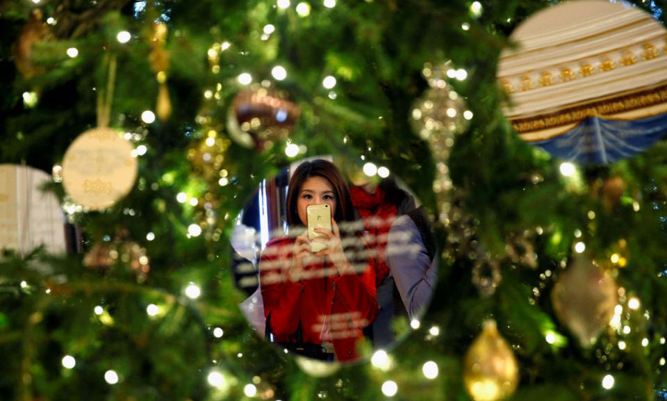 Eine Reporterin macht ein Selfie im Weißen Haus in Washington und spiegelt sich dabei in der Weihnachtsbaumdekoration im Blue Room. (Bild: Kevin Lamarque/Reuters)