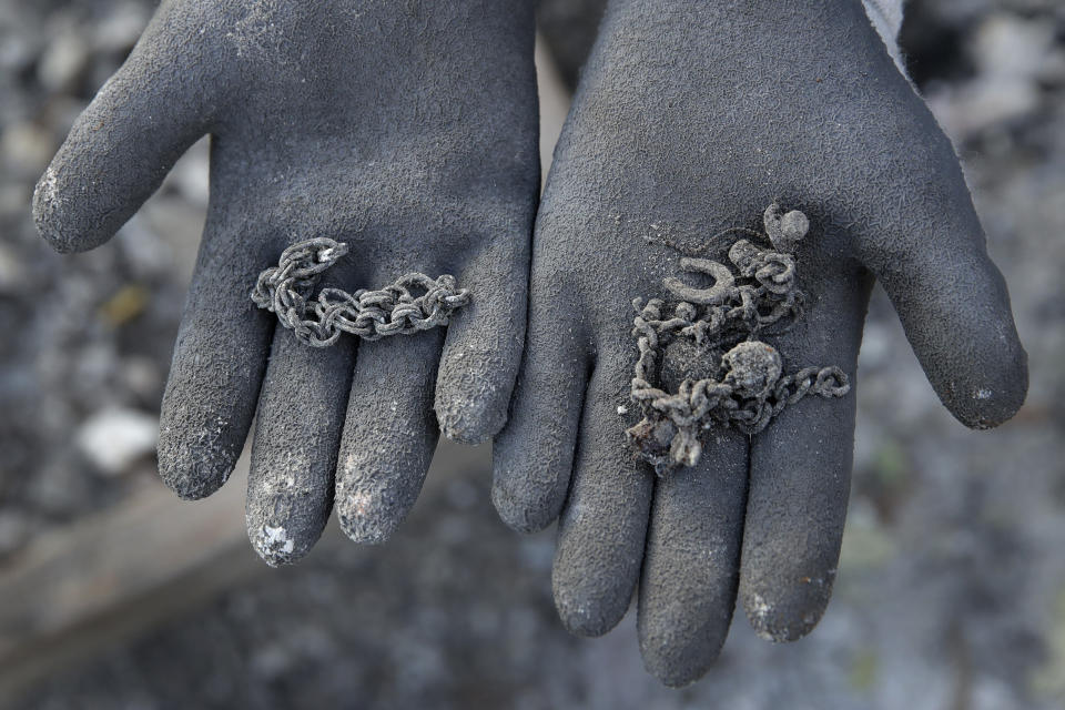 A friend of Bernadette Laos displays jewelry salvaged from her home that was destroyed by the Kincade Fire near Geyserville, Calif., Thursday, Oct. 31, 2019. (AP Photo/Charlie Riedel)