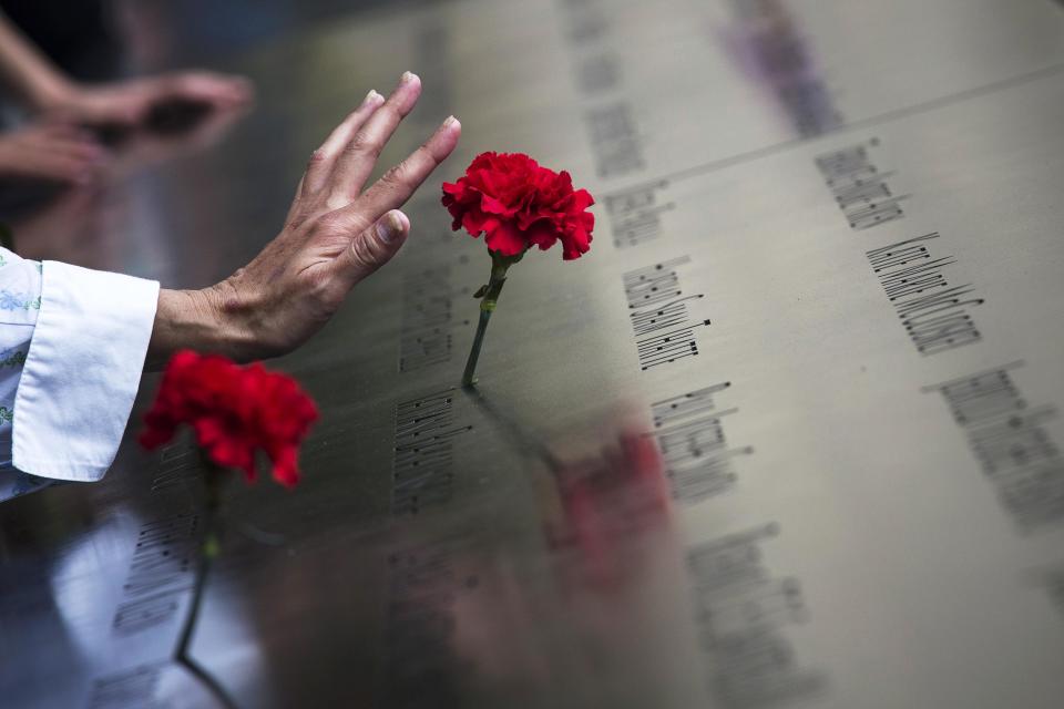 A woman touches a carnation left on a name inscribed into the North Pool during 9/11 Memorial ceremonies marking the 12th anniversary of the 9/11 attacks on the World Trade Center in New York