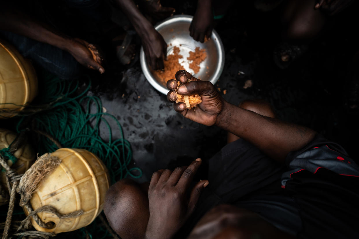 Gambian fishermen holding fistfuls of fishmeal. (Fábio Nascimento / The Outlaw Ocean Project)