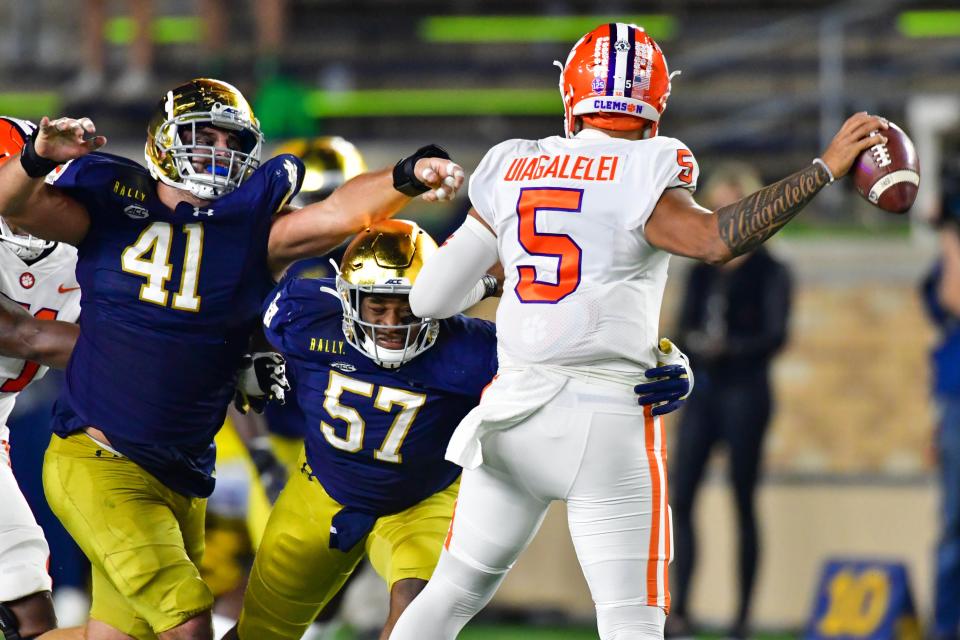 Notre Dame nose guard Kurt Hinish (41) and defensive tackle Jayson Ademilola (57) pressure Clemson quarterback D.J. Uiagalelei (5) on Saturday.