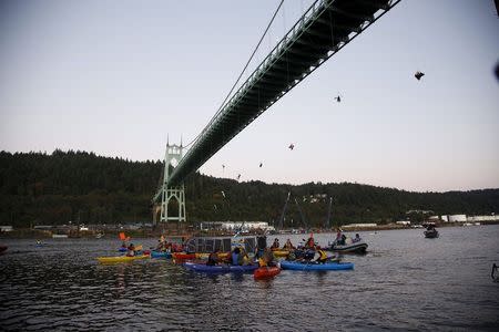 Greenpeace activists hang under the St. Johns Bridge and kayakers gather in the Williamette River in an attempt to block the Shell leased icebreaker, MSV Fennica, in Portland, Oregon, July 29, 2015. REUTERS/Steve Dipaola/Greenpeace/Handout