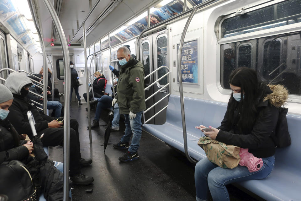 People in face masks ride the subway in New York, Monday, April 13, 2020. Gov. Andrew Cuomo says New York's death toll from coronavirus has topped 10,000, with hospitals still seeing 2,000 new patients a day. (AP Photo/Ted Shaffrey)