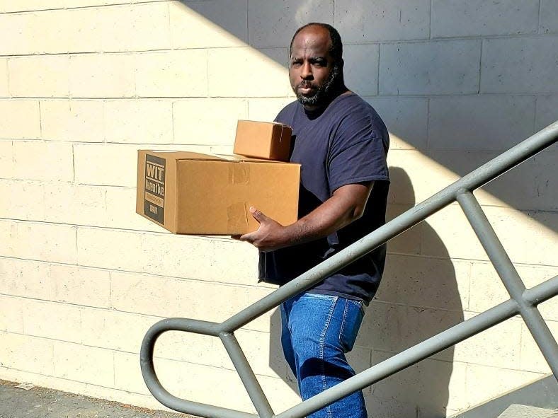 A man holding a brown box walks down a flight of stairs.