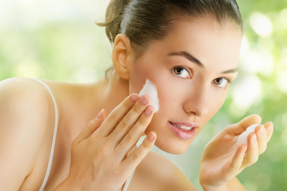 A woman applies face cream.