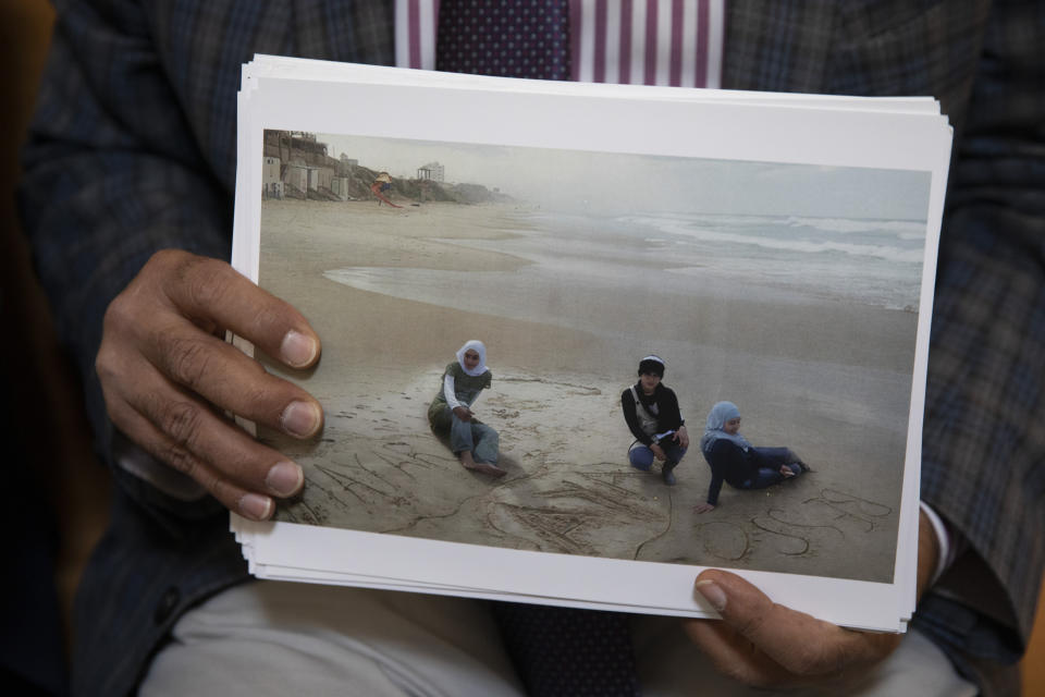 FILE - Palestinian Dr. Izzeldin Abuelaish holds a photograph of his daughters and niece on the beach in Gaza as he sits inside inside Israel's Supreme Court for a hearing on his demand for an apology from Israel over a 2009 tank strike that killed three of his daughters and a niece in the Gaza Strip, in Jerusalem, Nov. 15, 2021. The Court on Wednesday, Nov. 24, 2021, rejected an appeal from Abuelaish, who has been on a 13-year campaign to seek justice for what he says was a terrible mistake by the Israeli military. The Israeli government has argued that the military is not liable for wartime actions. (AP Photo/Ariel Schalit, File)