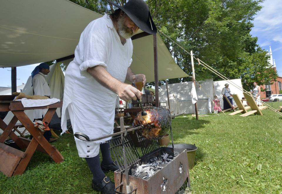 Frank D'Aurora, with the French Creek Living History Association, brushes apple juice onto a ham he was roasting during Waterford Heritage Days in 2019.