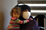 An Albanian woman carries a child as she waits at the Rafik Hariri International Airport, during an operation to take them back home to Albania from al-Hol, northern Syria, in Beirut, Lebanon, Tuesday, Oct. 27, 2020. The repatriation of four children and a woman related to Albanian nationals who joined Islamic extremist groups in Syria "is a great step" to be followed by more repatriations, Albania's prime minister said Tuesday in Beirut. (AP Photo/Bilal Hussein)