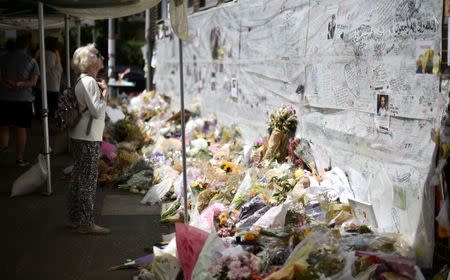 A woman looks at flowers, tributes and messages left for the victims of the fire at the Grenfell apartment tower in North Kensington, London, Britain, June 23, 2017. REUTERS/Hannah McKay