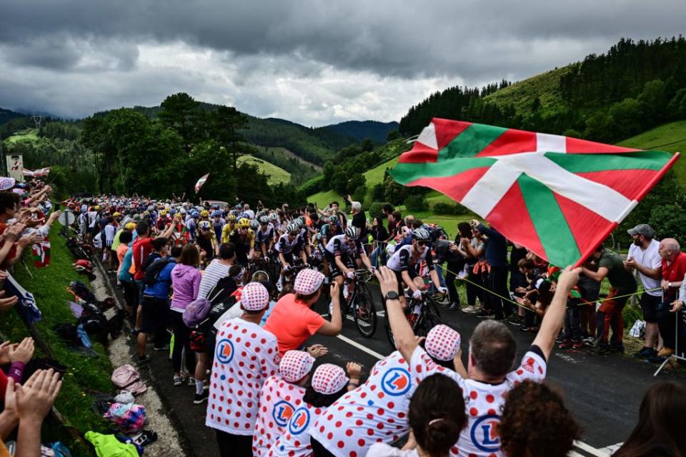 Spectators line the race route with Basque regional flags as the pack of riders cycles during the 2nd stage of the 110th edition of the Tour de France cycling race 2089 km between VitoriaGasteiz and San Sebastian in northern Spain on July 2 2023 Photo by Marco BERTORELLO  AFP Photo by MARCO BERTORELLOAFP via Getty Images