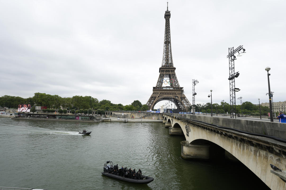 Special forces ride boats along the Senne River with the Eiffel Tower seen in the distance in Paris, France, prior to the opening ceremony of the 2024 Summer Olympics, Friday, July 26, 2024. (AP Photo/Andy Wong)