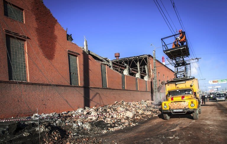 Workers repair a power line near the wall of a local zinc plant that was damaged by a shockwave from a meteor in the Urals city of Chelyabinsk, on February 15, 2013