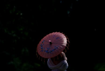 A woman holds an umbrella in Lafayette Park near the White House during a heat wave in Washington