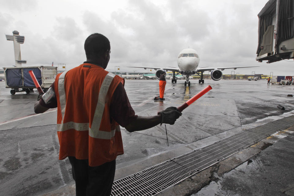 In this Wednesday, Aug. 1 2012 photo, a Delta Air Lines ramp agent assists a pilot as he pulls into a gate at JFK International airport in New York. Travelers still have to put up with packed planes, rising fees and unpredictable security lines, but they are missing fewer business meetings or chances to tuck their kids into bed. Nearly 84 percent of domestic flights arrived within 15 minutes of their schedule time in the first half of the year, the best performance since the government started tracking such data in 1988. (AP Photo/Mary Altaffer)