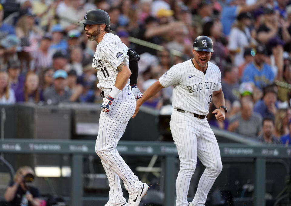 Colorado Rockies' Jake Cave, left, celebrates with third base coach Warren Schaeffer as Cave rounds the bases after hitting a solo home run off Milwaukee Brewers starting pitcher Tobias Myers in the sixth inning of a baseball game Thursday, July 4, 2024, in Denver. (AP Photo/David Zalubowski)