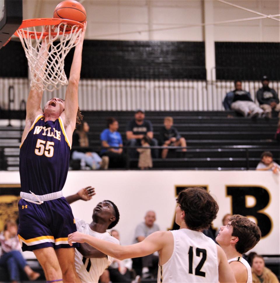 Wylie's Harrison Heighten (55) drives to the basket as Abilene High's Sami Kanayo defends and Sawyer Moss (12) and a teammate look on in the second half. The Eagles beat Wylie 46-38 in in the nondistrict game Tuesday, Dec. 14, 2021, at Eagle Gym.