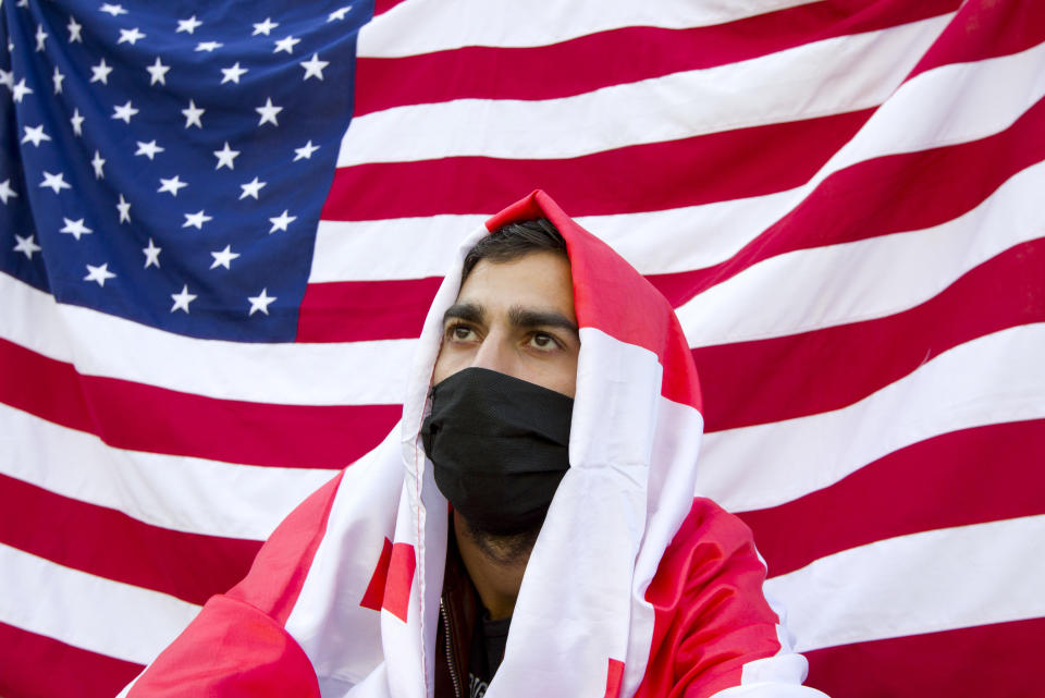 A supporters of the ex-President Mikhail Saakashvili's United National Movement, wearing a face mask to help curb the spread of the coronavirus, sits in front of an American national flag during a rally to protest the election results at the parliament's building in Tbilisi, Georgia, Sunday, Nov. 1, 2020. Preliminary election results show that Georgia's ruling party won the country's highly contested parliamentary election. But the opposition refused to recognize Sunday's results as valid, saying they were manipulated. (AP Photo/Shakh Aivazov)
