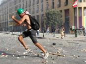 A demonstrator runs for cover after throwing stones at riot police with a tennis racket, during a protest in Beirut