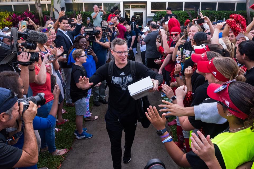 Florida Atlantic men's basketball coach Dusty May high-fives fans as he walks towards the team buses at Baldwin Arena on Wednesday, March 29, 2023, in Boca Raton, FL. On Wednesday morning, the FAU men's basketball team departed for Houston, Texas, where they will play against San Diego State in the NCAA Tournament semi-final on Saturday.