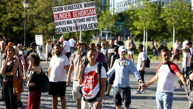 A demonstrator holds a placard in front of a human chain near the Chancellery during a protest against the government's COVID restrictions, in Berlin, August 1, 2020. 