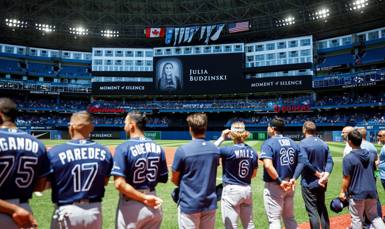 Tampa Bay Rays players and staff stand for a moment of silence on the death of Julia Budzinski, the eldest daughter of first base coach Mark Budzinski, ahead of a game against the Tampa Bay Rays at Rogers Centre on July 3, 2022 in Toronto, Canada. (Cole Burston / Getty Images)