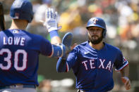 Texas Rangers' Isiah Kiner-Falefa (9) gets a high five from teammate Nathaniel Lowe (30) after scoring on a sacrifice fly by Yonny Hernandez during the sixth inning of a baseball game, Sunday, Aug. 8, 2021, in Oakland, Calif. (AP Photo/D. Ross Cameron)