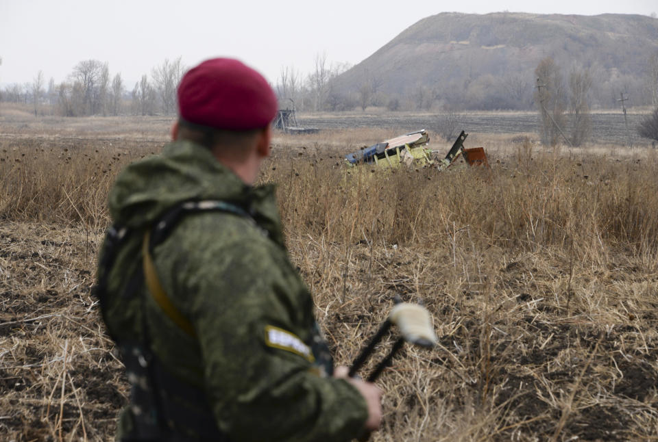 FILE - In this file photo dated Tuesday, Nov. 11, 2014, Pro-Russian rebel fighter guards one of the areas of the Malaysia Airlines Flight 17 plane crash in the village of Rossypne, Donetsk region, eastern Ukraine. Five years after a missile blew Malaysia Airlines Flight 17 out of the sky above eastern Ukraine, relatives and friends of those killed will gather Wednesday July 17, 2019, at a Dutch memorial to mark the anniversary.(AP Photo/Mstyslan Chernov, FILE)