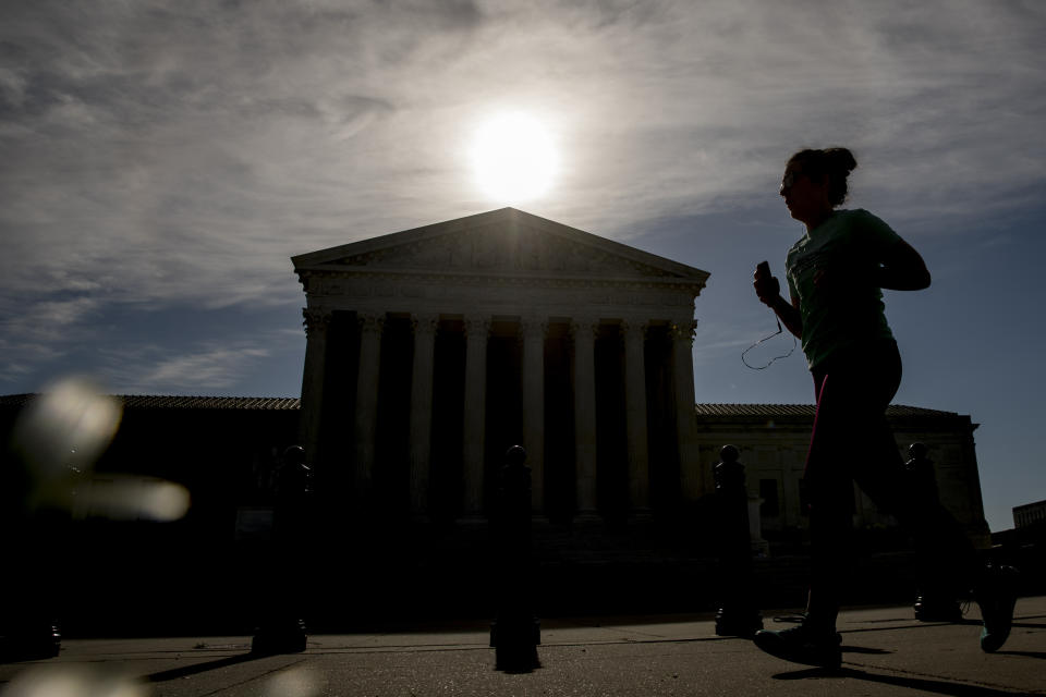 A woman runs past the Supreme Court where the justices will hold arguments by telephone for the first time ever, Monday, May 4, 2020, in Washington. (AP Photo/Andrew Harnik)