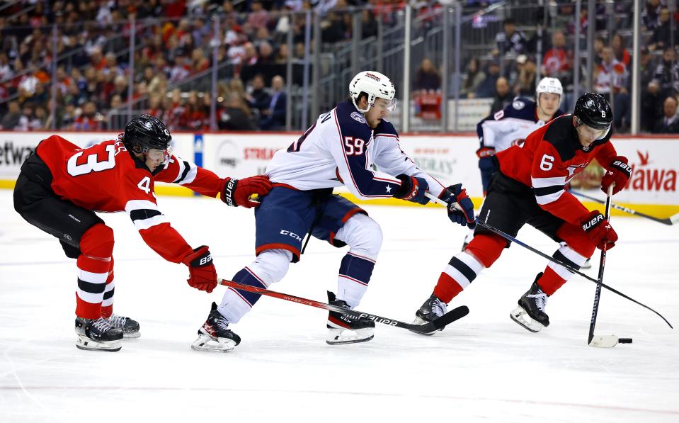 Columbus Blue Jackets right wing Yegor Chinakhov (59) battle for the puck against New Jersey Devils defensemen Luke Hughes (43) and John Marino (6) during the first period of an NHL hockey game Wednesday Dec. 27, 2023, in Newark, N.J. (AP Photo/Noah K. Murray)