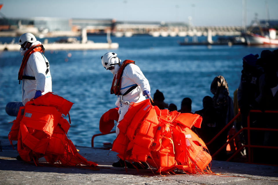 Rescuers carry life vests of migrants after arriving on a rescue boat at the port of Malaga