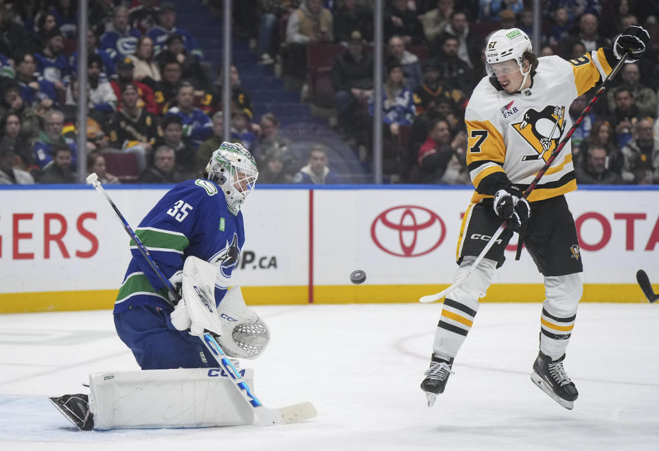 Vancouver Canucks goalie Thatcher Demko, left, makes a save as Pittsburgh Penguins' Rickard Rakell jumps in front of him during the second period of an NHL hockey game Tuesday, Feb. 27, 2024, in Vancouver, British Columbia. (Darryl Dyck/The Canadian Press via AP)