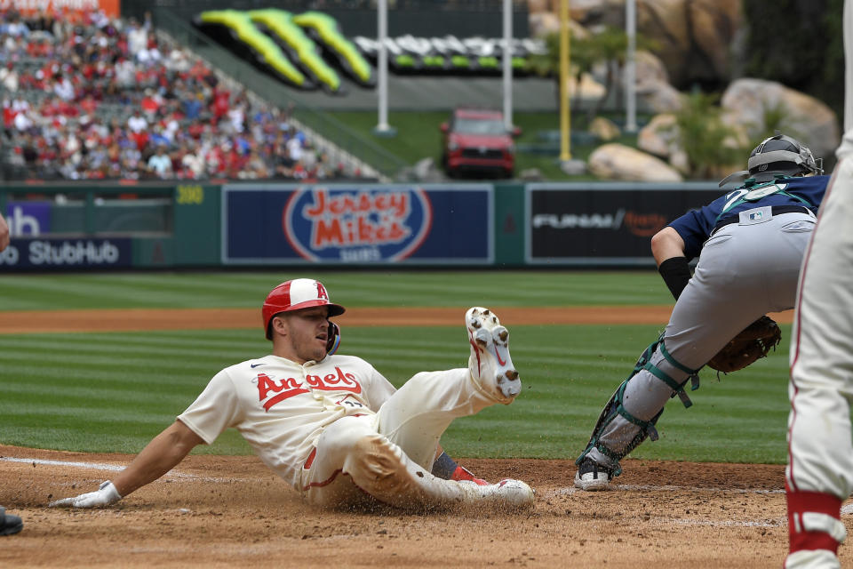 Los Angeles Angels' Mike Trout, left, scores on a double by Matt Thaiss as Seattle Mariners catcher Cal Raleigh waits for the ball during the third inning of a baseball game Sunday, June 11, 2023, in Anaheim, Calif. (AP Photo/Mark J. Terrill)