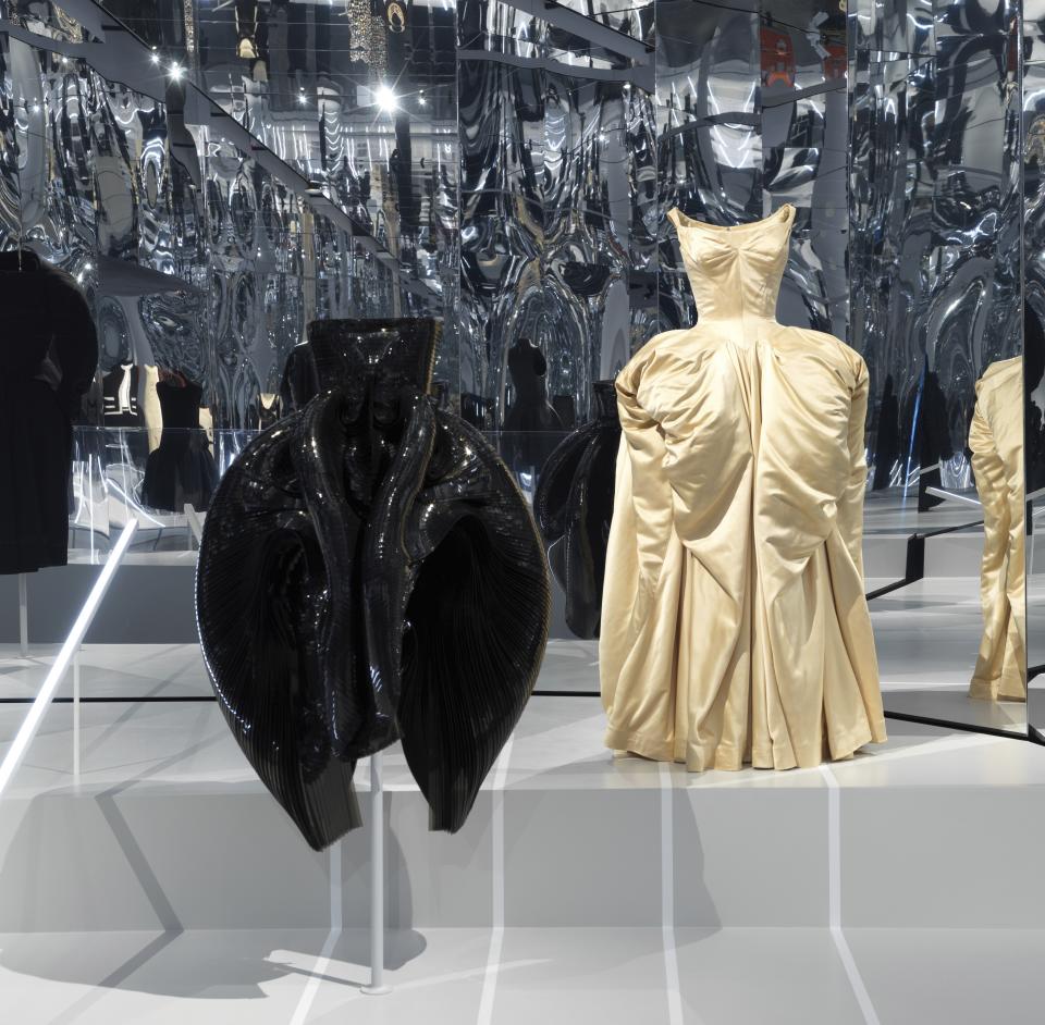 This image released by the Metropolitan Museum of Art in New York shows a black dress by Dutch designer Iris Van Herpen, left, and a ball gown by American designer Charles James, part of The Costume Institute’s exhibition "About Time: Fashion and Duration," tracing 150 years of fashion. (Anna-Marie Kellen/Metropolitan Museum of Art via AP)